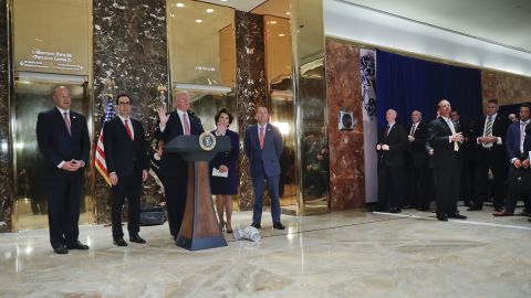 President Donald Trump speaks to the media in the lobby of Trump Tower. With Trump are from left, National Economic Council Director Gary Cohn, Treasury Secretary Steven Mnuchin, Transportation Secretary Elaine Chao and OMB Director Mick Mulvaney. 
