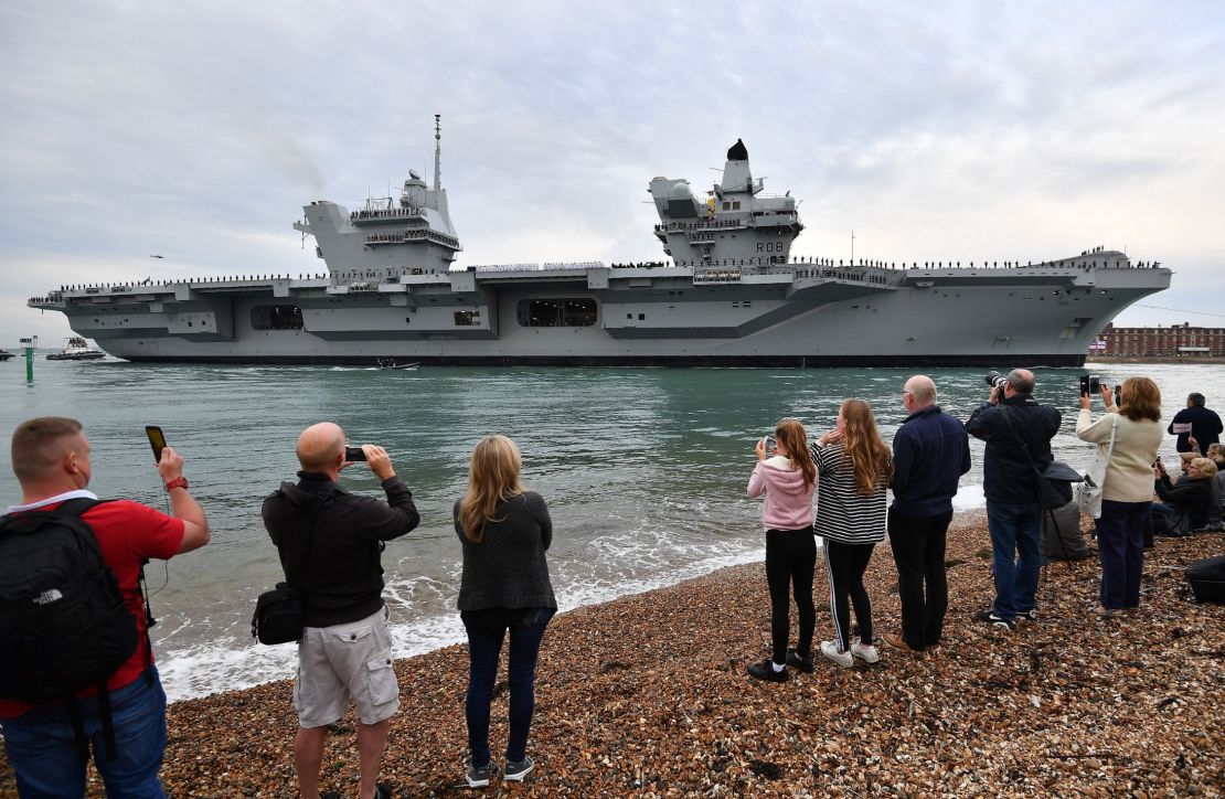 People line the shore to watch as tug boats maneuver the 65,000-ton British aircraft carrier HMS Queen Elizabeth into Portsmouth Harbour.