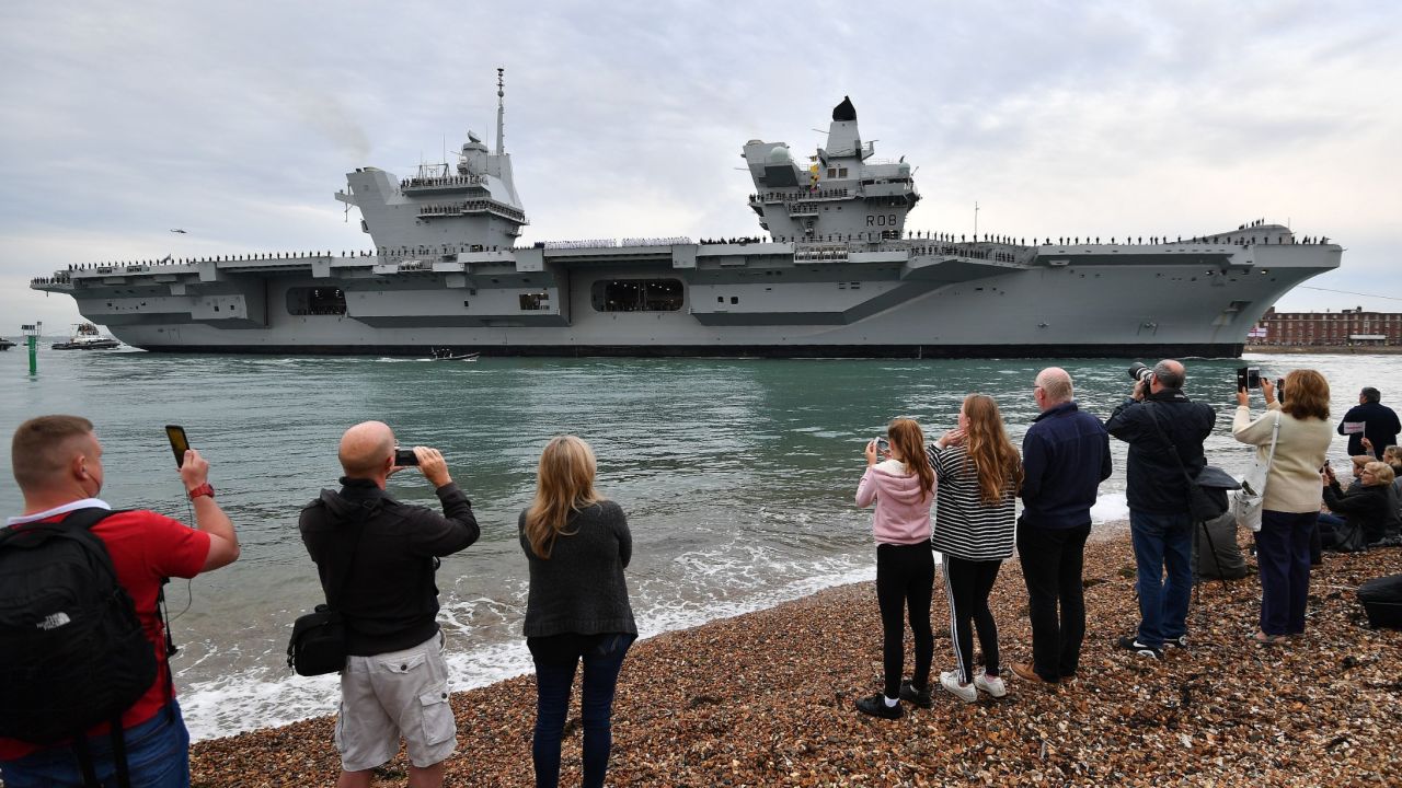 People line the shore to watch as tug boats maneuver the 65,000-ton British aircraft carrier HMS Queen Elizabeth into Portsmouth Harbour.