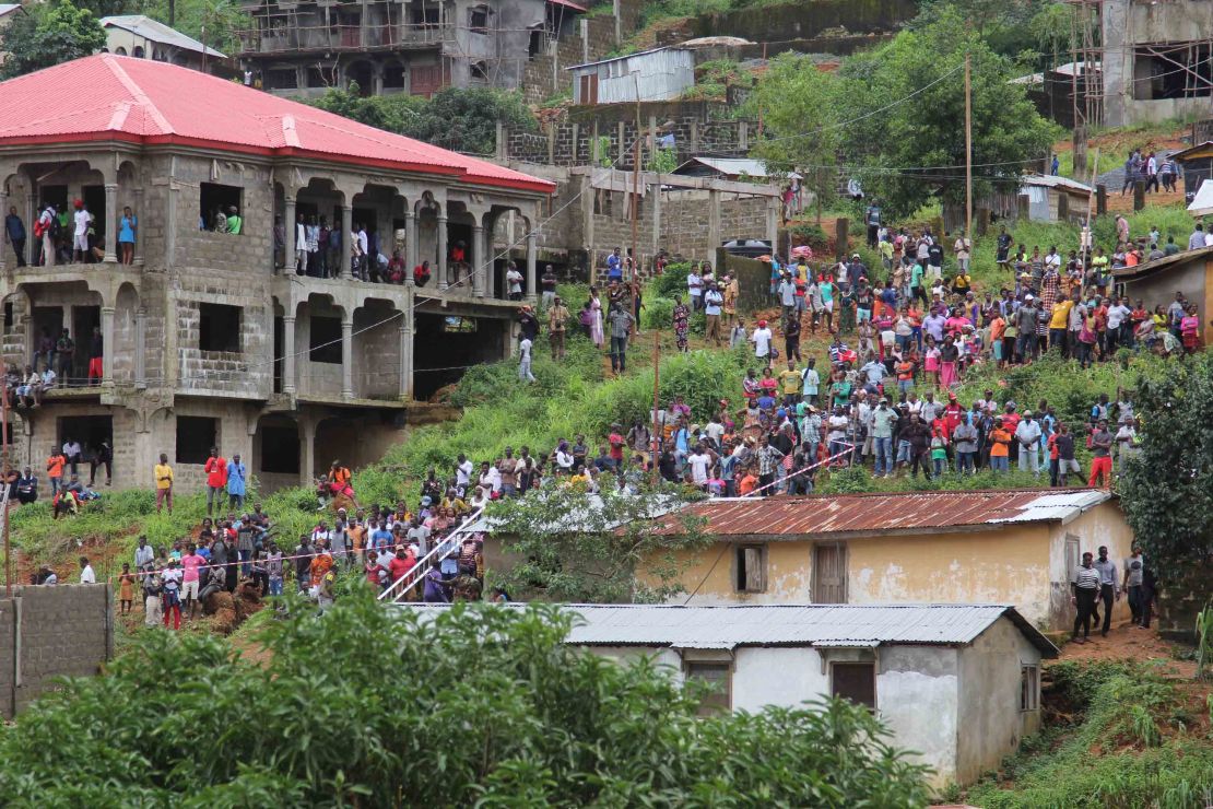 Residents look on as workers remove wreckage from the Regent area of Freetown, after landslides struck the capital of the west African state on Monday.