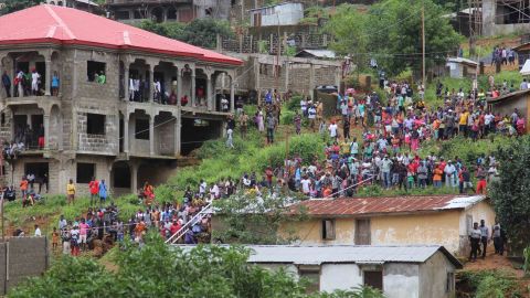 Residents look on as workers remove wreckage from the Regent area of Freetown, after landslides struck the capital of the west African state on Monday.