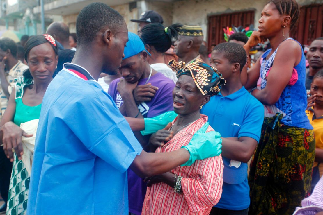 A relative of a mudslide victim receives comfort Wednesday at the Freetown morgue.