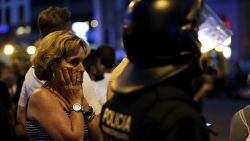 A woman gestures as she is escorted out by Spanish policemen outside a cordoned off area after a van ploughed into the crowd, killing 13 persons and injuring over 80 on the Rambla in Barcelona on August 17, 2017.