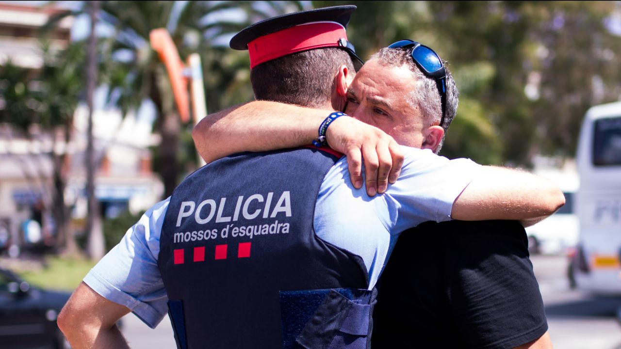 A man embraces a police officer in Cambrils on August 18. Earlier in the day, officers had engaged in a shootout with five attackers who drove a car into several pedestrians. All five were shot dead by police, four of them by one officer, police said.
