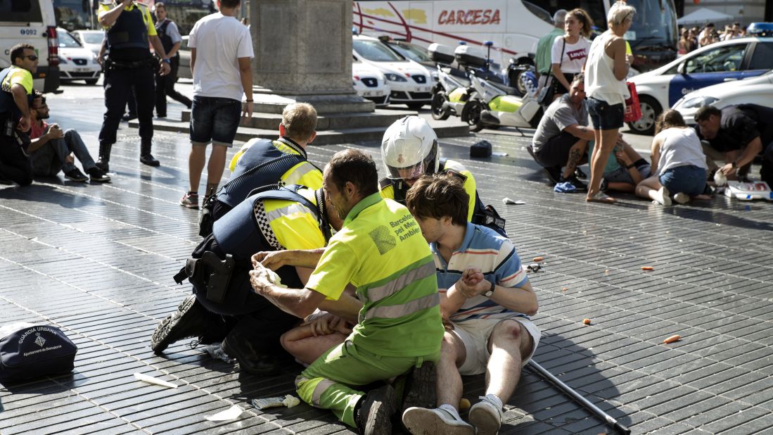 Medics and police tend to injured people near the scene of the attack in Barcelona.
