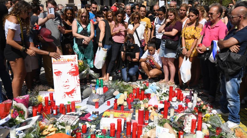 People stand next to flowers, candles and other items set up on the Las Ramblas boulevard in Barcelona as they pay tribute to the victims of the Barcelona attack, a day after a van ploughed into the crowd, killing 13 persons and injuring over 100 on August 18, 2017.
Police hunted for the driver who rammed a van into pedestrians on an avenue crowded with tourists in Barcelona, leaving 13 people dead and more than 100 injured, just hours before a second assault in a resort along the coast. / AFP PHOTO / PASCAL GUYOT (Photo credit should read PASCAL GUYOT/AFP/Getty Images)