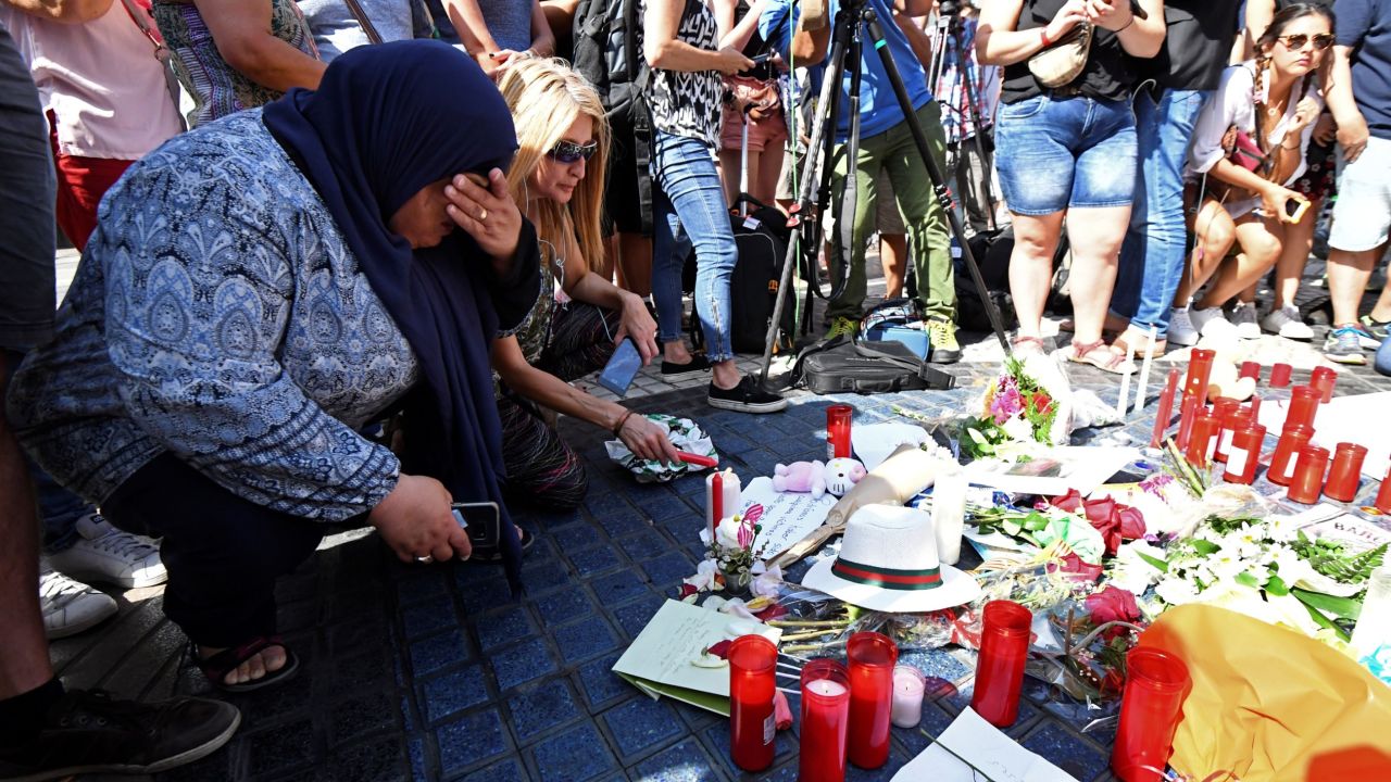 People gather next to flowers, candles and other items set up on the Las Ramblas boulevard in Barcelona as they pay tribute to the victims of the Barcelona attack, a day after a van ploughed into the crowd, killing 13 persons and injuring over 100 on August 18, 2017.
Police hunted for the driver who rammed a van into pedestrians on an avenue crowded with tourists in Barcelona, leaving 13 people dead and  more than 100 injured, just hours before a second assault in a resort along the coast. / AFP PHOTO / PASCAL GUYOT        (Photo credit should read PASCAL GUYOT/AFP/Getty Images)