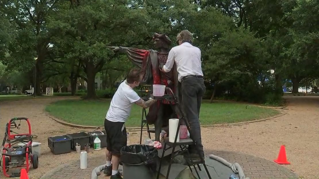 Men cleaning the statue after it was vandalized.
