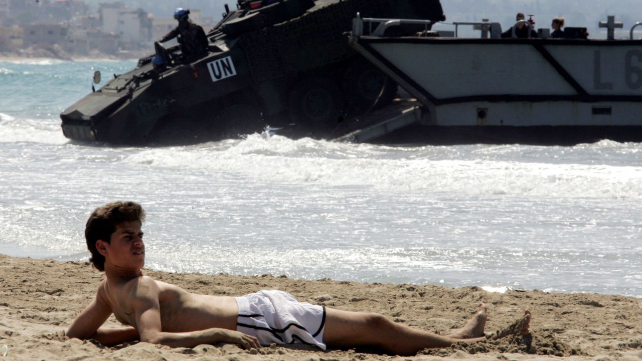 In 2006, militant group Hezbollah fought a war with neighboring Israel, resulting in the deployment of UN forces. Here, a boy lies on the beach in Tyre as Spanish UN troops arrive in the city.