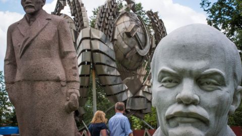 A picture taken on July 11, 2017 shows sculptures of the founder of the Soviet Union Vladimir Lenin next to a state emblem of the USSR at the Muzeon park of Arts in Moscow.