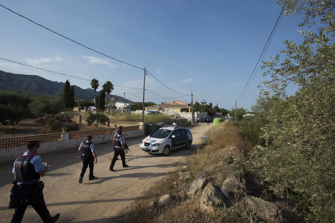 Armed police walk down a dirt road toward the scene of the explosion in Alcanar.