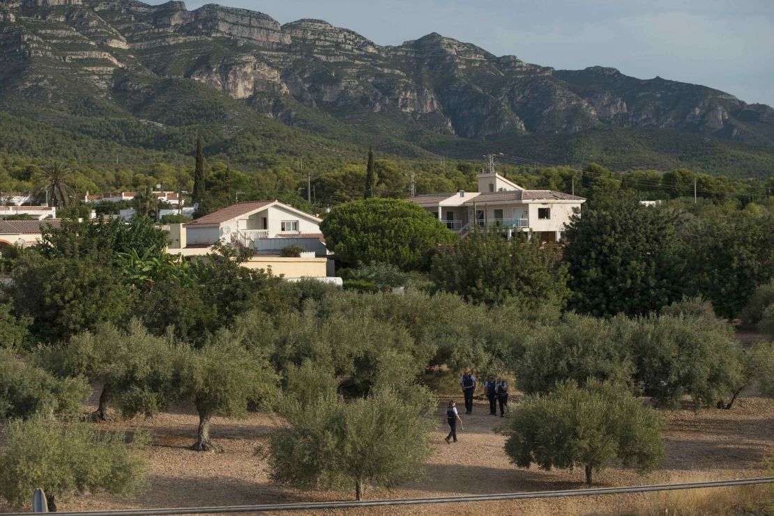 A policewoman picks up debris in the olive grove surrounding the bomb site.
