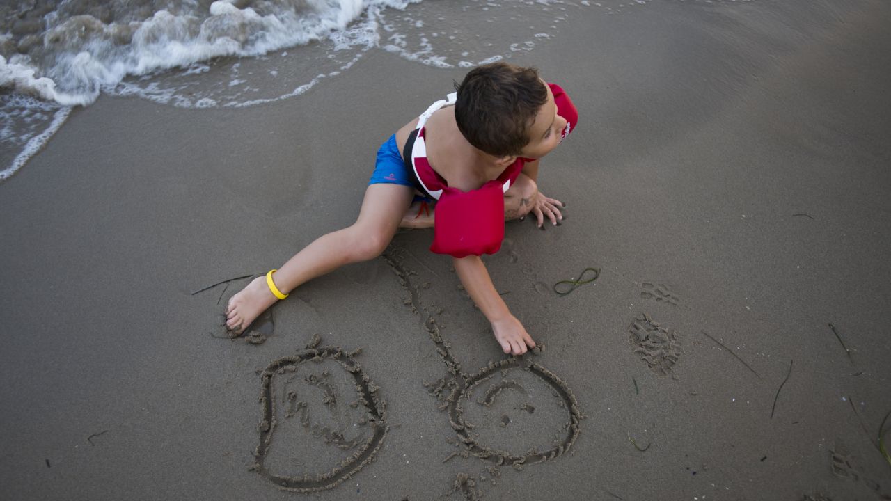 Romera and Gonzalez' 4-year-old son sketches in the sand on Playa Cementera.