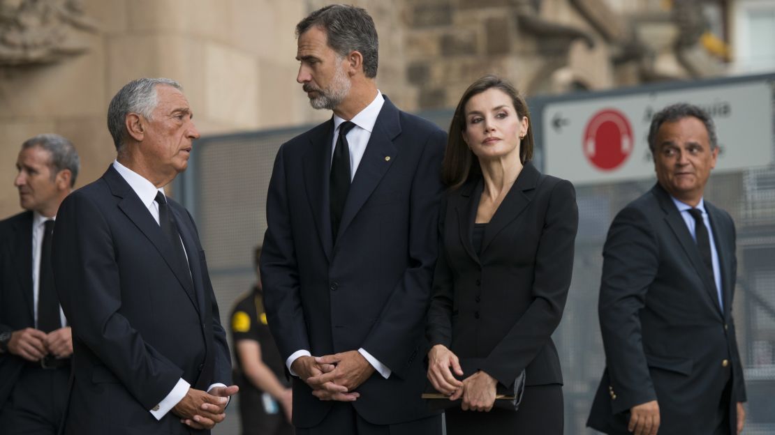 Spain's King Felipe VI, center, speaks to officials before the mass, while his wife Queen Letizia looks on at the crowd outside.