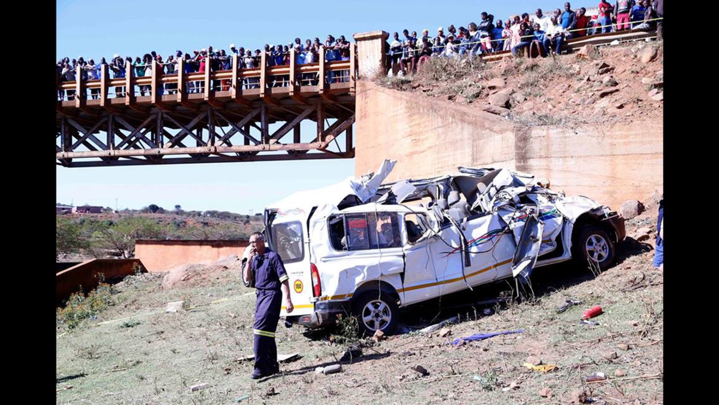 Residents watch from a bridge as authorities investigate a deadly minibus crash near Pietermaritzburg, South Africa.