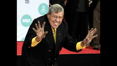 Lewis holds up his cement covered hands during a 2014 ceremony to add his hand prints and footprints to the sidewalk at the TCL Chinese Theatre in Hollywood. 