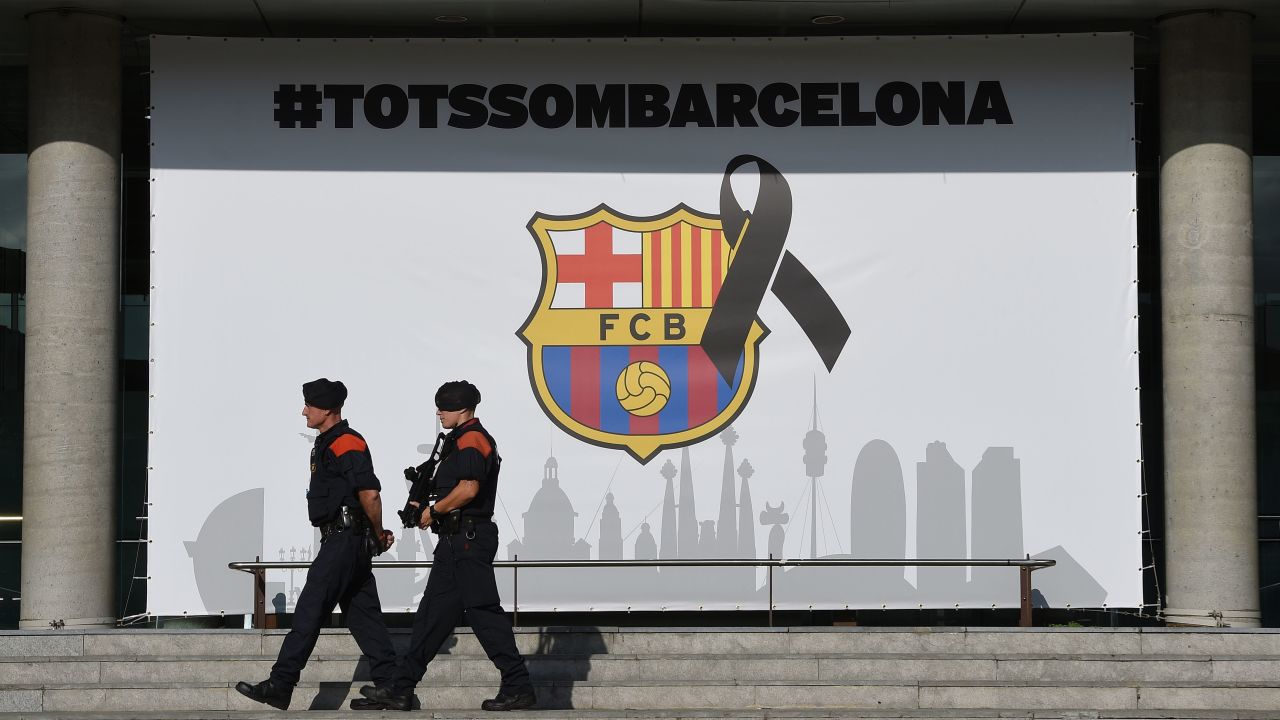 Armed Catalan policemen -- Mosso d'Esquadra -- walk by the FC Barcelona logo, to which a black ribbon was added.