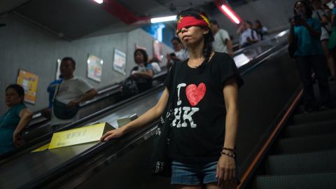 A protester covers her eyes with a China flag to imply Goddess of Justice during the rally supporting Wong, Law and Chow in Hong Kong's Central district Sunday. 
