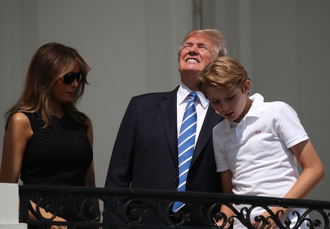 President Donald Trump looks up toward the Solar Eclipse while standing with his wife first lady Melania Trump and their son Barron, on the Truman Balcony at the White House on August 21, 2017.