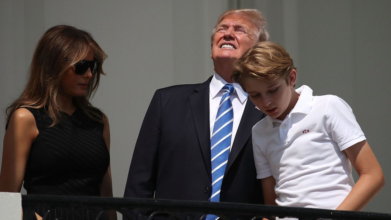 President Donald Trump looks up toward the Solar Eclipse while standing with his wife first lady Melania Trump and their son Barron, on the Truman Balcony at the White House on August 21, 2017.