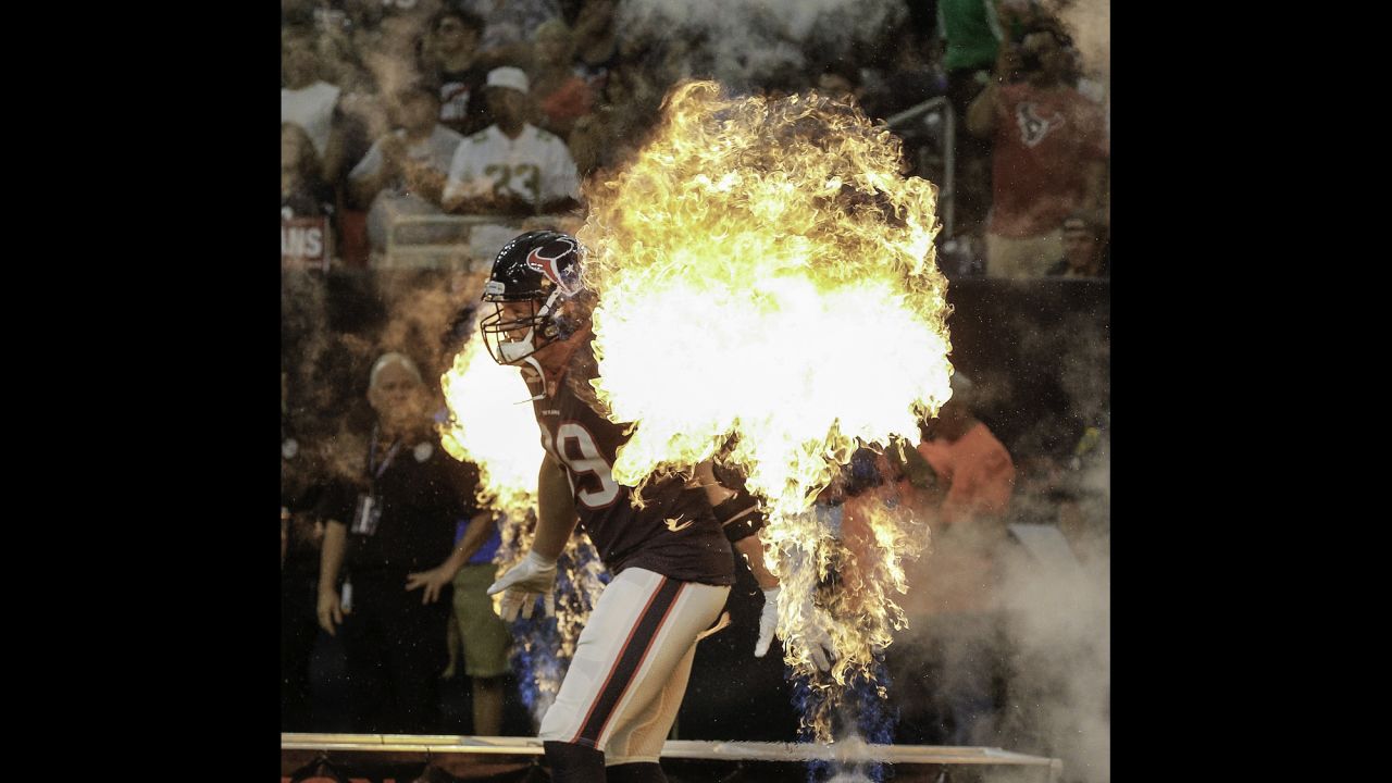 Houston defensive end J.J. Watt runs between pyrotechnics before an NFL preseason game on Saturday, August 19.