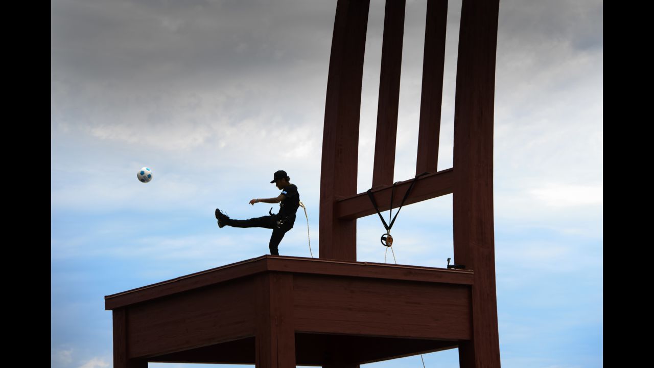 Brazilian soccer star Neymar kicks a ball off the Broken Chair sculpture in Geneva, Switzerland, on Tuesday, August 15. The sculpture is a symbol for landmine victims around the world.