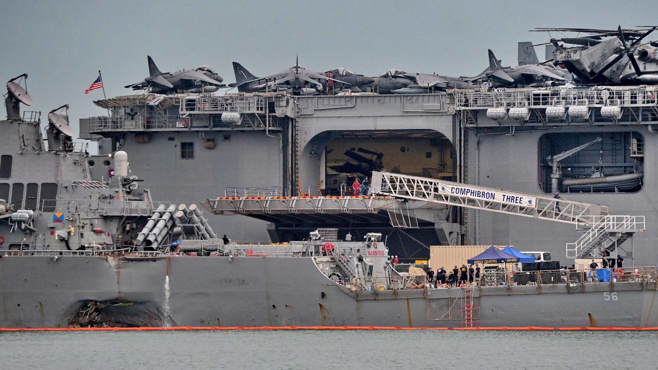 The guided-missile destroyer USS John S. McCain (foreground), seen with a hole on its portside after a collision with a tanker, docks next to the USS America (behind) at Changi naval base in Singapore on August 22, 2017.
The US Navy announced a fleet-wide global investigation after the latest in a series of warship accidents left 10 sailors missing and five injured. Chief of Naval Operations Admiral John Richardson ordered commanders within a week to set aside time, perhaps "one or two days", for crews to sit down together after the destroyer USS John S. McCain collided with a tanker off Singapore early on August 21. / AFP PHOTO / Roslan RAHMAN        (Photo credit should read ROSLAN RAHMAN/AFP/Getty Images)
