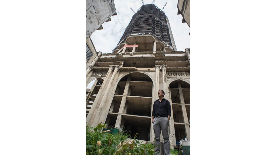 Pansit Torsuwan, owner of the Sathorn Unique Tower, stands beside the abandoned structure.