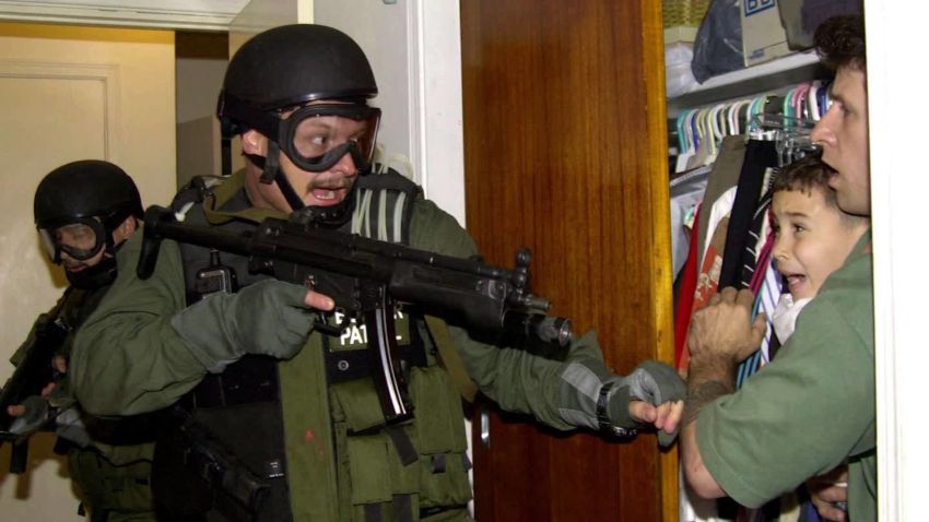 In this third of seven sequential photos, Elian Gonzalez is held in a closet by Donato Dalrymple, one of the two men who rescued the boy from the ocean, right, as government officials search the home of Lazaro Gonzalez for the young boy, early Saturday morning, April 22, 2000, in Miami. Armed federal agents seized Elian Gonzalez from the home of his Miami relatives before dawn Saturday, firing tear gas into an angry crowd as they left the scene with the weeping 6-year-old boy.