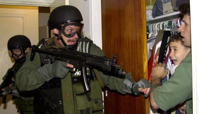 In this third of seven sequential photos, Elian Gonzalez is held in a closet by Donato Dalrymple, one of the two men who rescued the boy from the ocean, right, as government officials search the home of Lazaro Gonzalez for the young boy, early Saturday morning, April 22, 2000, in Miami. Armed federal agents seized Elian Gonzalez from the home of his Miami relatives before dawn Saturday, firing tear gas into an angry crowd as they left the scene with the weeping 6-year-old boy. 