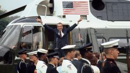 As he boards the White House helicopter after resigning the presidency, Richard M. Nixon smiles and gives the victory sign.