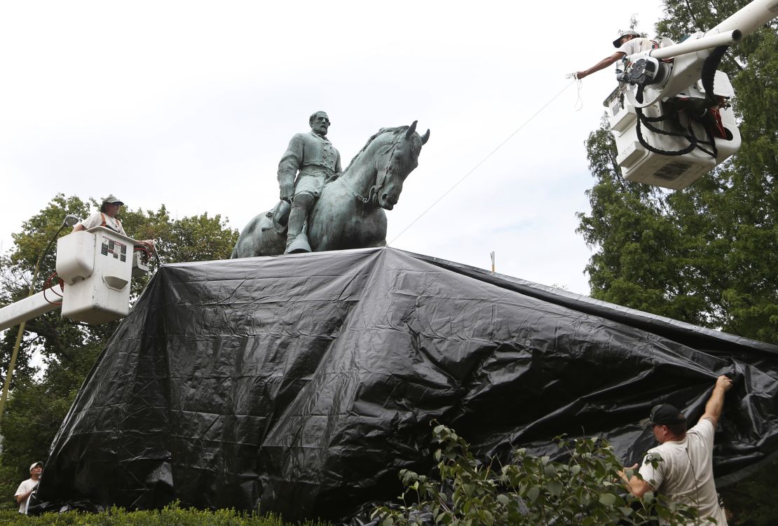 City workers drape a tarp over the statue of Confederate General Robert E. Lee on Wednesday.