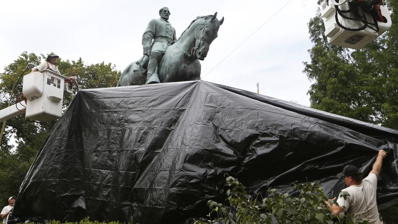 City workers drape a tarp over the statue of Confederate General Robert E. Lee on Wednesday.