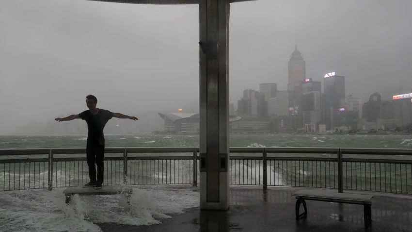 A man plays with strong wind caused by typhoon Hato on the waterfront of Victoria Habour in Hong Kong, Wednesday, Aug. 23, 2017. A powerful typhoon barreled into Hong Kong on Wednesday, forcing offices and schools to close and leaving flooded streets, shattered windows and hundreds of canceled flights in its wake.  (AP Photo/Vincent Yu)