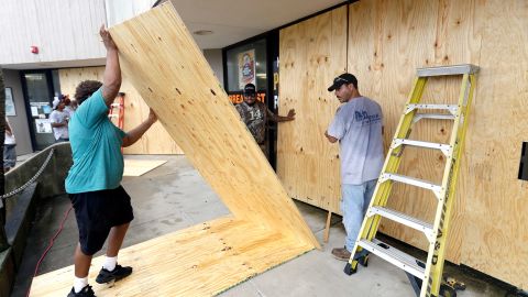 Christopher Beafneaux, left, Ernesto Villarreal, center, and Roman Lopez board up windows of a business in Galveston.