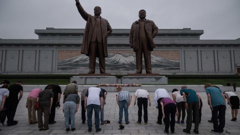 A group of tourists bow before statues of late North Korean leaders Kim Il Sung and Kim Jong Il , in Pyongyang on July 23, 2017.