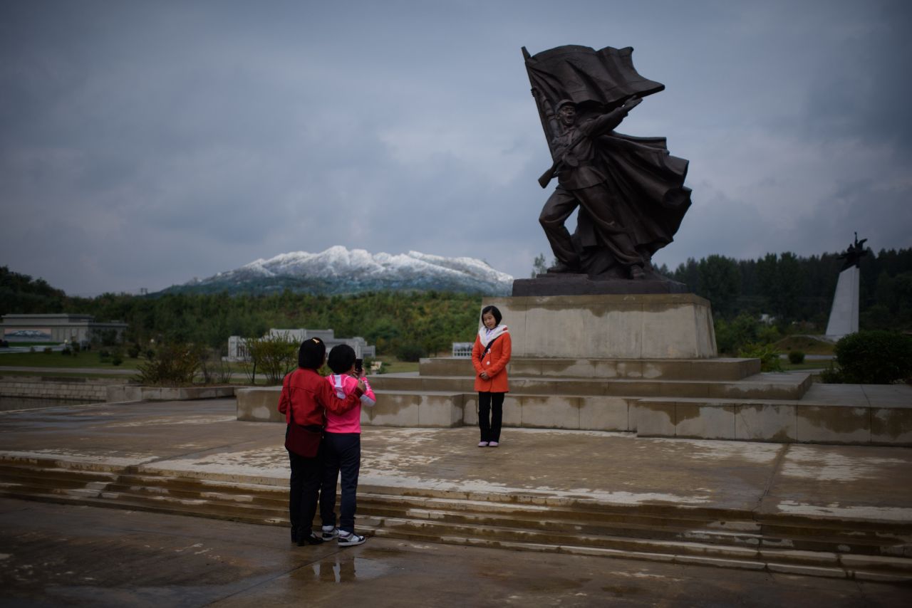 <strong>Moving mountains: </strong>Tourists pose with a miniature statue, in front of a model of Mount Paektu (an active volcano) at a folk park on the outskirts of Pyongyang.