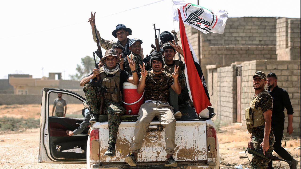 Fighters of the Popular Mobilisation Units flash the victory gesture as they sit in the back of a pickup truck during the advance in the eastern part of Tal Afar on Friday.