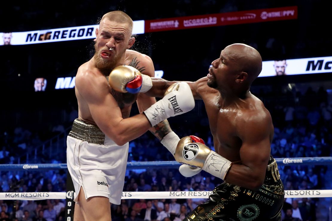(R-L) Floyd Mayweather Jr. throws a punch at Conor McGregor during their super welterweight boxing match on August 26, 2017.