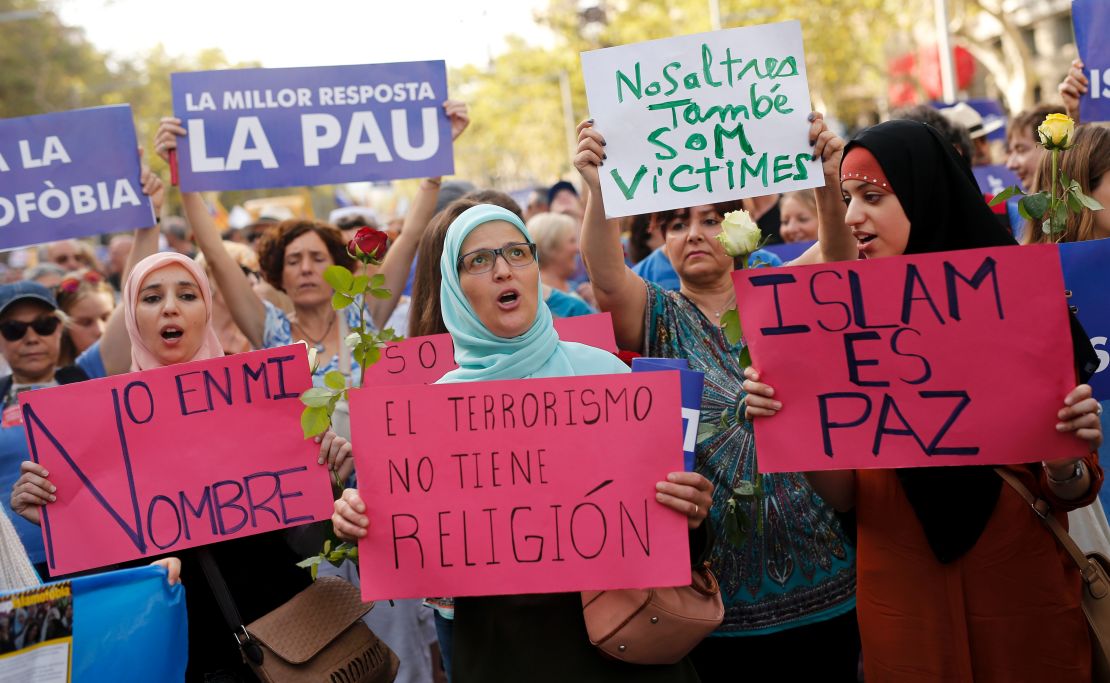 Muslim women hold placards reading "Not in my name," "Terrorism doesn't have a religion" and "Islam is Peace."