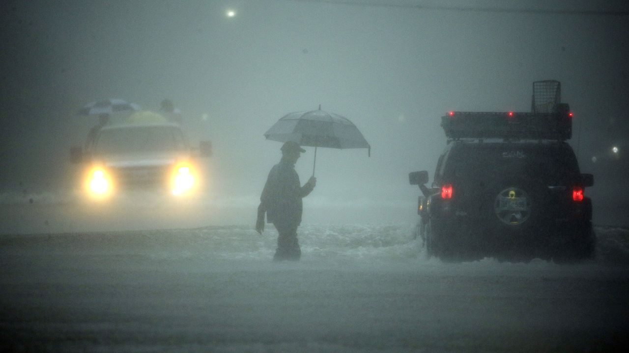 A man walks through floodwaters from Tropical Storm Harvey as he evacuates his home on Sunday, August 27, 2017, in Houston, Texas.