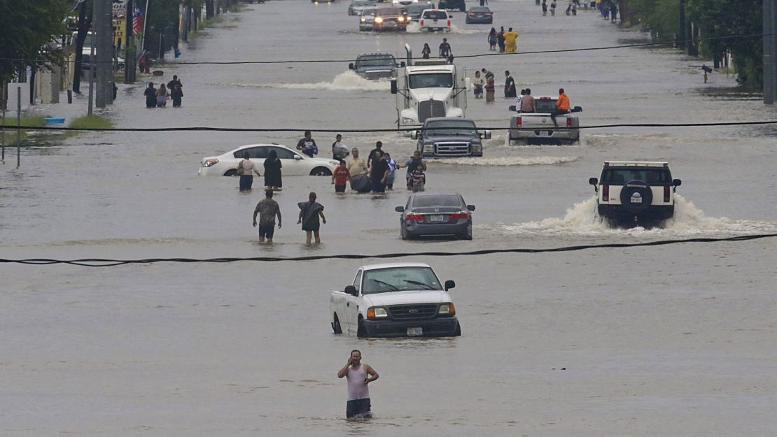 People walk through the flooded streets of Houston on August 27, 2017, after Hurricane Harvey dumped record rains.