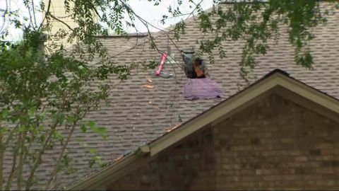 An evacuated Houston house shows where its residents broke through from the attic to escape.