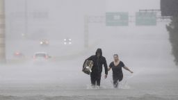 Two people walk down a flooded section of Interstate 610 in floodwaters from Tropical Storm Harvey on Sunday, Aug. 27, 2017, in Houston.