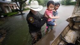 Fort Bend County Sheriff Troy Nehls and Lucas Wu lift Ethan Wu into an airboat as they are evacuated at the Orchard Lakes subdivision in Fort Bend County, Texas, on August 27.