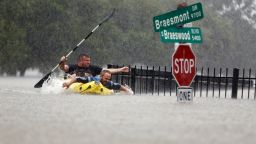 Two men try to beat the current pushing them down an overflowing Brays Bayou in Houston on August 27.