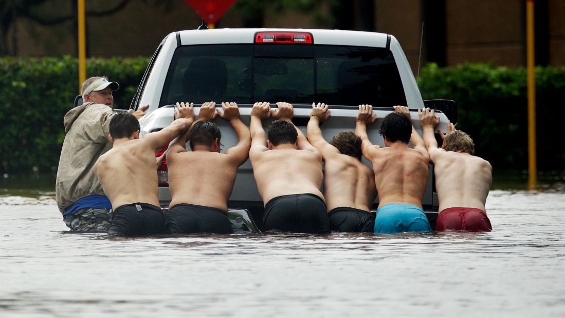 People push a stalled pickup through a flooded street in Houston.