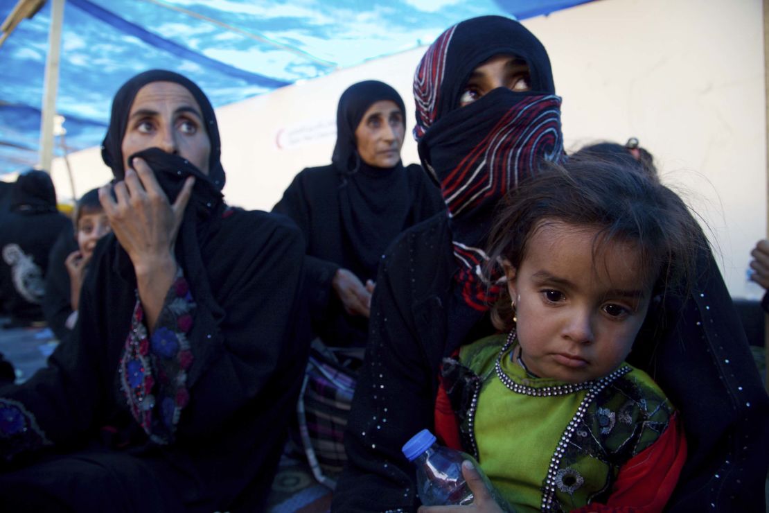 Displaced Iraqi women and children sit on the ground on the outskirts of Tal Afar on Saturday.