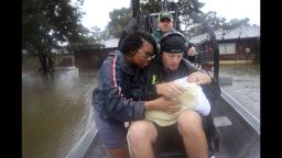 Shardea Harrison looks at her 3 week old baby Sarai Harrison being held by Dean Mize as he and Jason Legnon used his airboat to rescue them from their home in Houston on August 28.