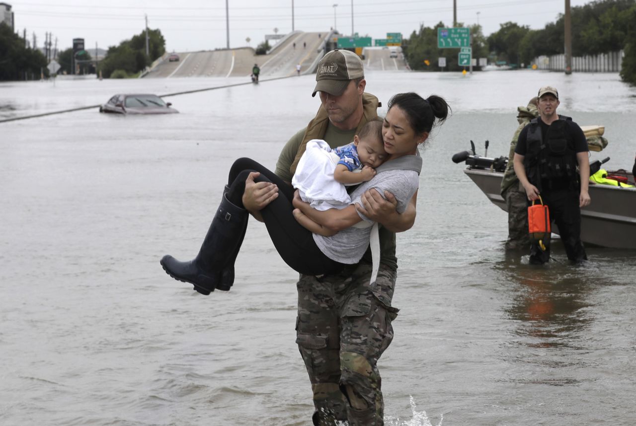 Houston police officer Daryl Hudeck carries Catherine Pham and her 13-month-old son, Aiden, after rescuing them from floodwaters.